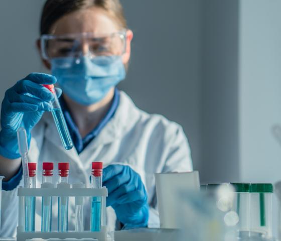 person holding vials of blue liquid in lab